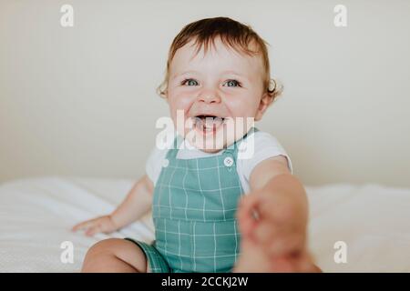 Primo piano della bambina che ride mentre si siede a letto a. casa Foto Stock