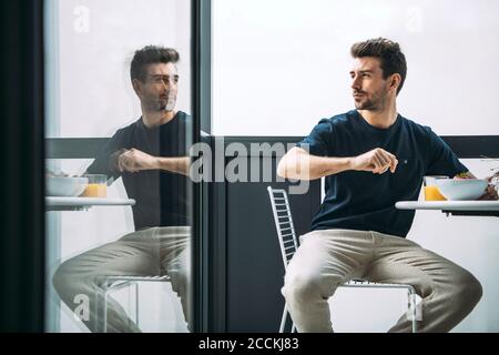 Uomo premuroso seduto sulla sedia al balcone nell'attico Foto Stock