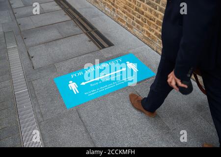 Gambe di uomini d'affari che camminano verso segno in città Foto Stock