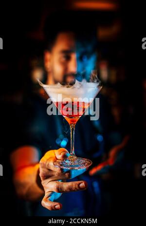 Primo piano del barman maschile che tiene un cocktail nel nightclub Foto Stock