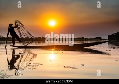 Myanmar, stato di Shan, Silhouette di pescatore tradizionale Intha sul lago di Inle al tramonto Foto Stock