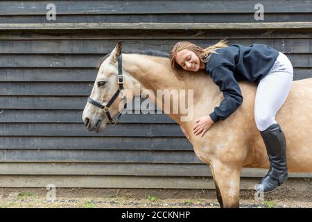 Giovane donna sdraiata sulla schiena del cavallo Foto Stock