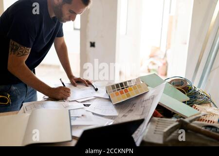 Uomo che lavora su piano di costruzione e orologio a colori Foto Stock