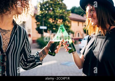 Una coppia felice di tostare le bottiglie di birra mentre ci si trova in città Foto Stock