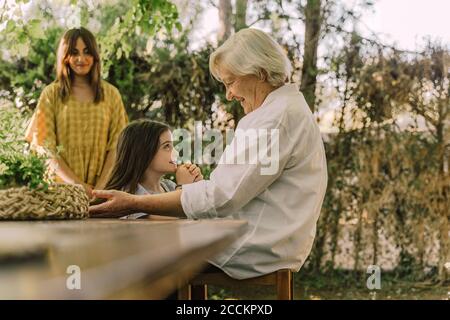 Donna che guarda la donna anziana che gioca con la nipote carina dentro iarda Foto Stock