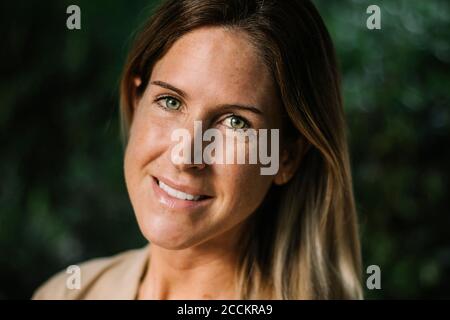 Primo piano di una donna mid adulta sorridente con occhi noccioli parcheggio Foto Stock