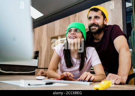 Felice coppia moderna di affari usando il computer alla scrivania in ufficio Foto Stock