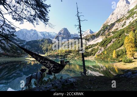 Donna escursionista in amaca e cane, Seebensee, Tirolo, Austria Foto Stock