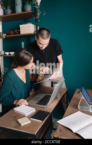 Giovane uomo e donna che discute di carta in ufficio domestico Foto Stock