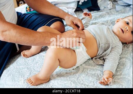 Padre col bambino che giace sul letto, cambiando i pannolini Foto Stock