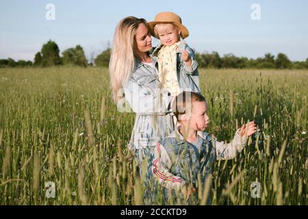 Madre sorridente con due bambini in campo Foto Stock