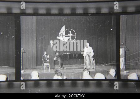 Bella fotografia in bianco e nero degli anni '70 di un uomo e di una donna che dà una performance formale sul palco. Foto Stock