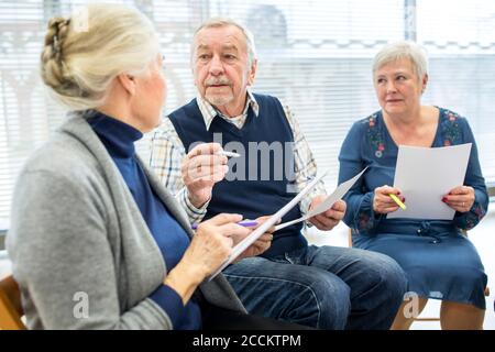 Anziani in gruppo di terapia in casa di pensione scrivere le note su fogli di carta Foto Stock