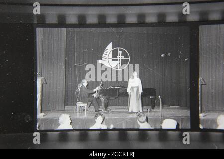 Bella fotografia in bianco e nero degli anni '70 di un uomo e di una donna che dà una performance formale sul palco. Foto Stock