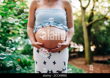 Donna incinta che tocca il ventre mentre si trova in posizione di parcheggio Foto Stock