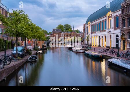 Olanda, Sud Olanda, Leiden, Barche ormeggiate lungo il canale della città del Reno al crepuscolo Foto Stock