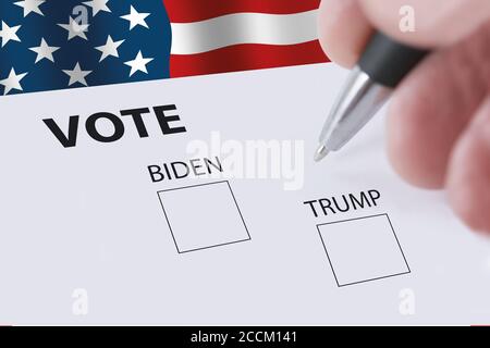 2020 votazione presidenziale con una mano sfocata che tiene una matita e caselle di controllo per il voto di Biden o Trump. Bandiera americana che oscilla nella b Foto Stock