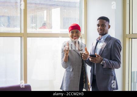I soci africani di affari discutono che cosa hanno visto sul cellulare e. gesturing pollici su Foto Stock