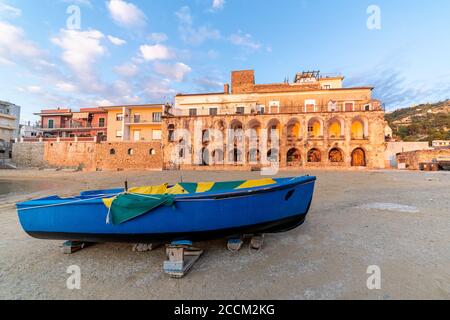 Antico edificio al tramonto a Santa Maria di Castellabate, Costa del Cilento, Italia. Luogo famoso, vista grandangolare con una barca in primo piano. Foto di alta qualità Foto Stock