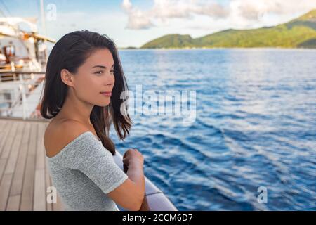 Nave da crociera di lusso vacanza viaggio donna barca passeggero che guarda il tramonto dal ponte. Bella ragazza turistica asiatica rilassante all'esterno godendo di vista Foto Stock