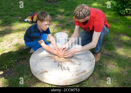 Il vasaio maschio insegna il ragazzo di lancio della ruota. Giugno 12,2019. Kiev, Ucraina Foto Stock