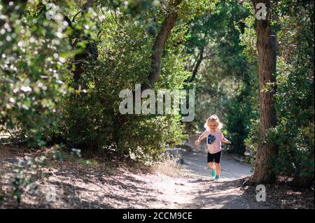 Felice bambina 2 yo facendo la sua prima escursione attraverso la foresta al Woodland Trail a Big Bear, California. Foto Stock