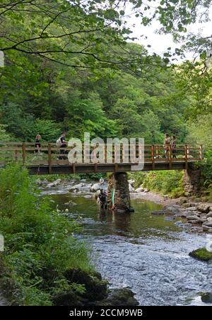 Pescatori e escursionisti al ponte dove Watersfeet sul fiume Lyn orientale, Lynmouth nel Devon nord Foto Stock