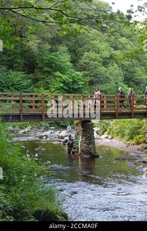 Pescatori e escursionisti al ponte dove Watersfeet sul fiume Lyn orientale, Lynmouth nel Devon nord Foto Stock