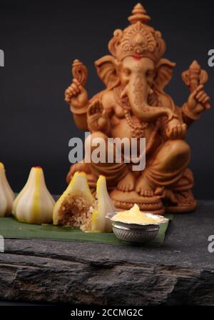 Modak - piatto tradizionale preparato con il festival di Ganpati in India, servito con burro chiarificato. Idolo Ganesh sullo sfondo Foto Stock