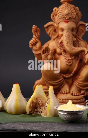 Modak - piatto tradizionale preparato con il festival di Ganpati in India, servito con burro chiarificato. Idolo Ganesh sullo sfondo Foto Stock