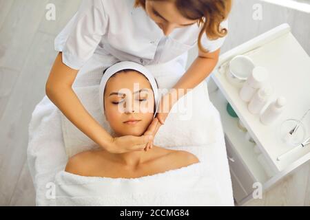 Cosmetologist che fa il massaggio lifting del viso per il viso e il collo delle donne Foto Stock