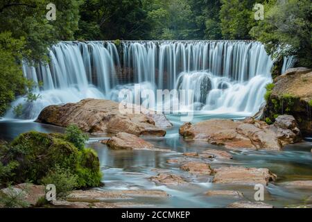 All'inizio di giugno, presso la Cascade de Saint Laurent le Minier, le acque fluiscono sulla caduta di acqua modificata messa in atto per controllare il flusso del fiume Vis Foto Stock