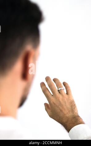 L'uomo bianco guarda la mano con un anello posto sul dito. Gioielli per uomo. Anello di innesto. Foto Stock