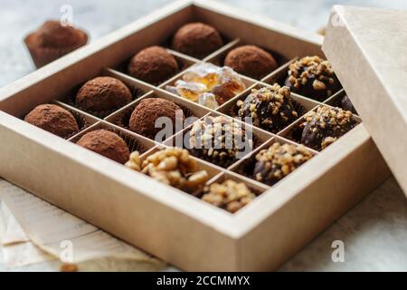 Set di tartufi al cioccolato con noci e cacao. Gustosa caramella rotonda. Un regalo delizioso in una scatola di carta Kraft. Concetto di vacanza. Messa a fuoco selettiva Foto Stock