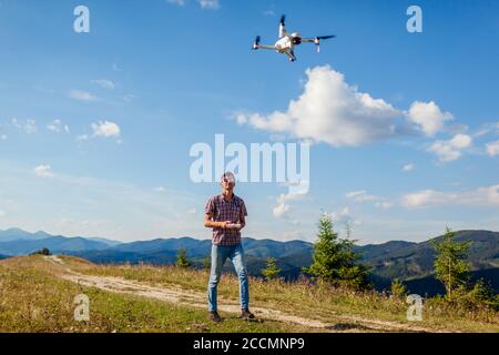 Video riprese con droni dei Carpazi estivi. Uomo che aziona il controller del copter in montagna. Natura turistica filmata Foto Stock