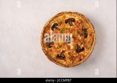 Quiche tradizionali francesi a torta con funghi e formaggio su uno sfondo chiaro e testurizzato, vista dall'alto, spazio copia Foto Stock