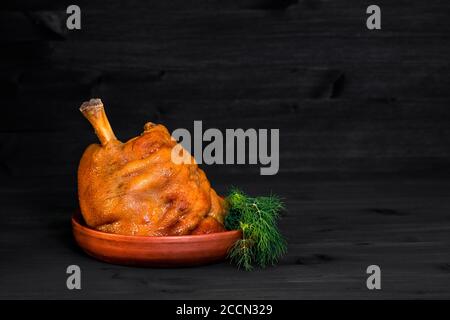 Salsa di maiale al forno con aneto verde in una padella di argilla su sfondo di legno scuro Foto Stock