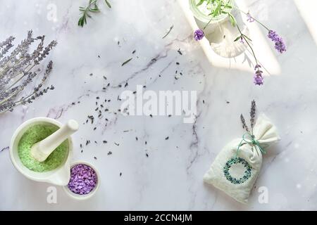 Bustine di lavanda fatte a mano e scrub allo zucchero fatto in casa. Fiori di lavanda freschi e secchi. Piatto su marmo bianco. Foto Stock