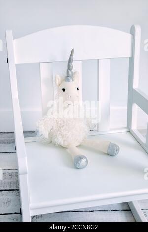 Peluche giocattolo unicorno su una sedia dondolo di un bambino Foto Stock