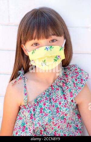 Ragazza di otto anni che indossa una maschera floreale Foto Stock