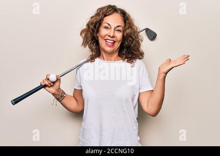 Media età bella sportivo che gioca a golf usando bastone e palla sfondo bianco che celebra il successo con sorriso felice e vincitore espresio Foto Stock