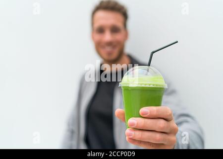 Salute uomo che beve perdita di peso verde frullato bevanda. Mano che tiene tazza di plastica di succo di verdure, dieta sana mangiare stile di vita Foto Stock