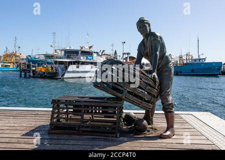 Scultura di un pescatore a Fremantle, Australia. Tributo all'industria della pesca. Barche da pesca e oceano dietro. West Coast, Australia Occidentale WA Foto Stock