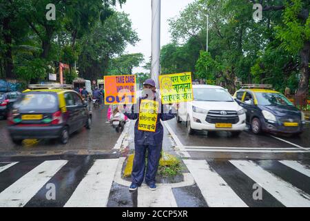 Una persona che ricorda alla gente di prendere le precauzioni adeguate per evitare di ottenere infettato dal virus della corona stando in piedi sulla strada con il messaggio scritto sui cartelli. Foto Stock