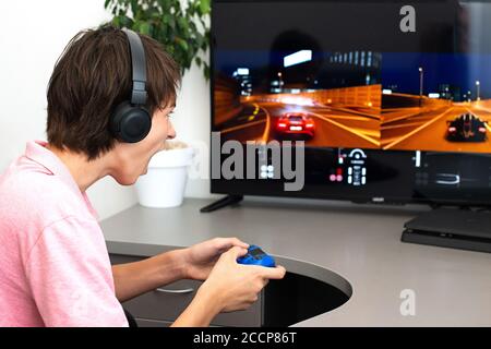 Orenburg, Russia, 19, giugno 2020. Sony PlayStation 4. Gran truismo sport. Teenager gioca un gioco per computer con cuffie e un joystick, console di gioco. Foto Stock