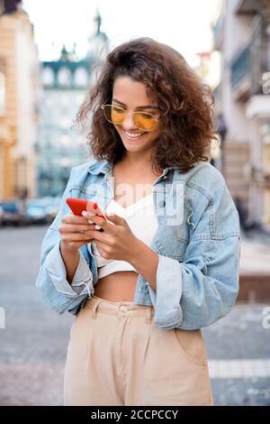 Ragazza ispanica teenager che chiacchiera con i social media sul suo smartphone. Foto Stock