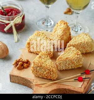 Camembert o brie alla griglia o al forno. Antipasto con delicatessen al sesamo con vino. Servito con noci e mirtillo (lingonberry, cowber Foto Stock