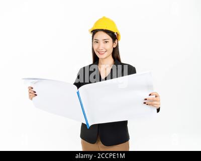 Giovane donna d'affari asiatica sorridente indossando tuta nera e casco di sicurezza giallo che tiene progetti di progettazione di carta piani. Ritratto di ingegnere femminile loo Foto Stock