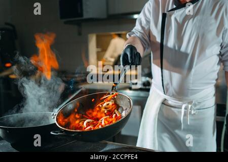 Cucina moderna. I cuochi preparano pasti sul fornello nella cucina del ristorante o albergo. Il fuoco in cucina. Foto Stock