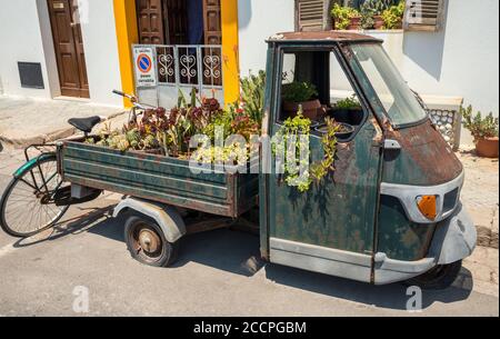 Un vecchio pickup a tre ruote Piaggio, riutilizzato come contenitore per impianti nella città di Gallipoli, Puglia meridionale, Italia. Foto Stock